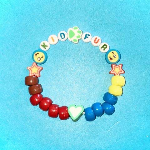 Photo of a bracelet with brown, red, blue, and yellow pony beads; smily face, star, heart, and paw print beads; and letter beads that spell “kid fur” (paw print bead is in between “kid” and “fur”)