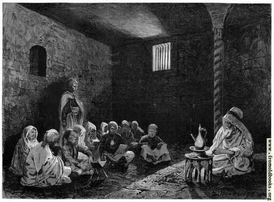 A bearded old man with Middle-Eastern head-dress sits holding a long rod or hookah, with a jug before him on an octagonal table. Across the floor from him are maybe 18 children cross-legged reading from books in their laps or on stands, and one standing person. It's a dark stone-walled chamber and a small high window has bars over it.