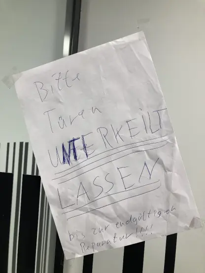 Handgeschriebener Zettel an einer Glastür:
Bitte Türen UNTERKEILT LASSEN
bis zur endgültigen
Reparatur!!!!

In Großbuchstaben und doppelt unterstrichen. Die Buchstaben waren zuerst klein geschrieben, wurden dann mit Großbuchstaben überkritzelt.