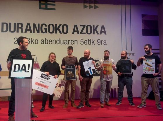 Durangoko azokako areto nagusian AtopiaRPG proiektuko zazpi kide zutik, beka-saria jasotzen. Ezkerrekoa atrilean dago, eta gauza garrantzitsuak esaten ari dela dirudi.