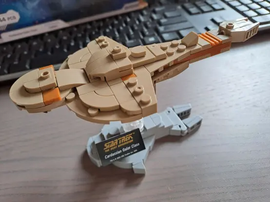 Isometric shot of an assembled Galor class starship made with BlueBrixx building bricks (a Lego alternative).

The ship is made of brownish bricks and its foundation's grey. The foundation's got roughly the same outline shape as the actual ship. It could also be an outline of the Cardassian Union logo, actually.

There's a plaque on the foundation reading Star Trek The Next Generation, Cardassian Galor Class. The whole thing is probably about 10cm in length and, including foundation, about half that height.

It's looking pretty cute!