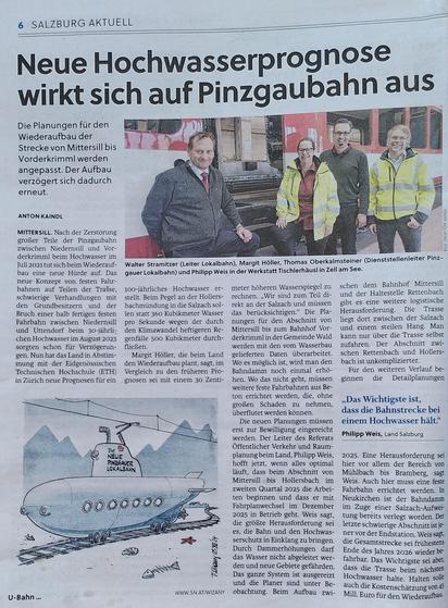 Foto von Zeitungsseite. Ein Foto von Menschen in Eisenbahnkleidung vor einem Rot-Weiß-Rot lackierten Personenwaggon, Text "Walter Stramitzer (Leiter Lokalbahn), Margit Höller, Thomas Oberkalmsteiner (Dienststellenleiter Pinzgauer Lokalbahn) und Philipp Weis in der Werkstatt Tischlerhäusl in Zell am See". Eine gezeichnete Karikatur (Wizany) mit einem U-Boot mit Rädern mit der Aufschrift "Neue Pinzgauer Lokalbahn" auf Schienen mit Oberleitung in einer bergigen Landschaft, in der neben den Gleisen eine Muschel, ein Seestern und Fischgräten liegen, Text "U-Bahn". Salzburger Nachrichten 3 Dec 2024 ANTON KAINDL