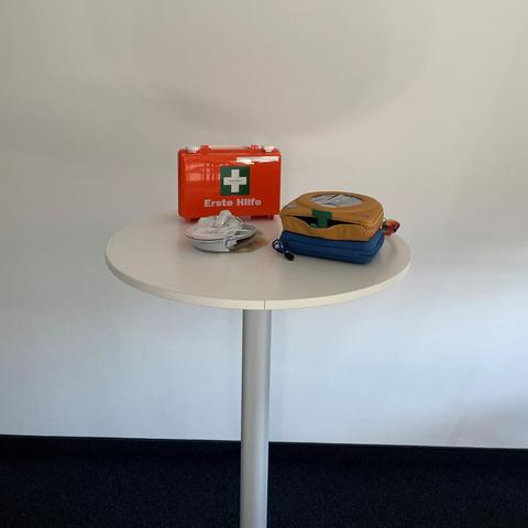 Erste Hilfe Kasten mit Defibrilator auf einem Stehtisch