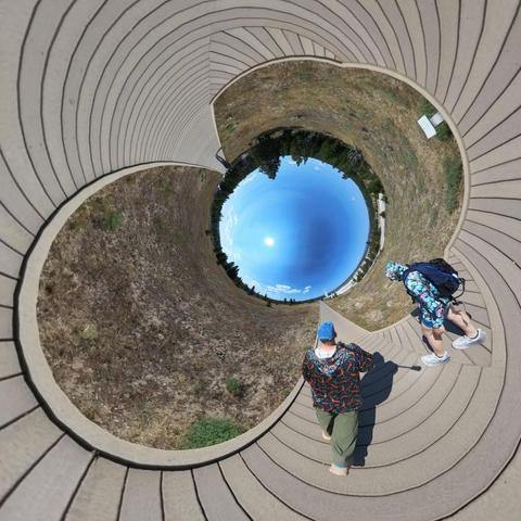 Photo of two people walking on a boardwalk in a hot springs area in Yellowstone National Park.