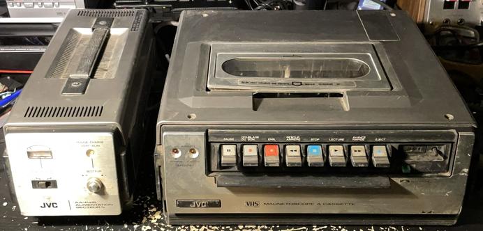 Un magnétoscope JVC HR-4100S et son alimentation externe sur un bureau
