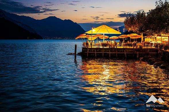 Summer evening at a lake in Switzerland. Golden lights from the terrace reflecting on the water.