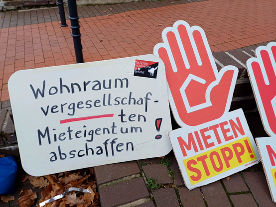 Ein Schild "Wohnraum vergesellschaften - Mieteigentum abschaffen!" steht neben Kampagnenmterial von "Mieten stopp!"