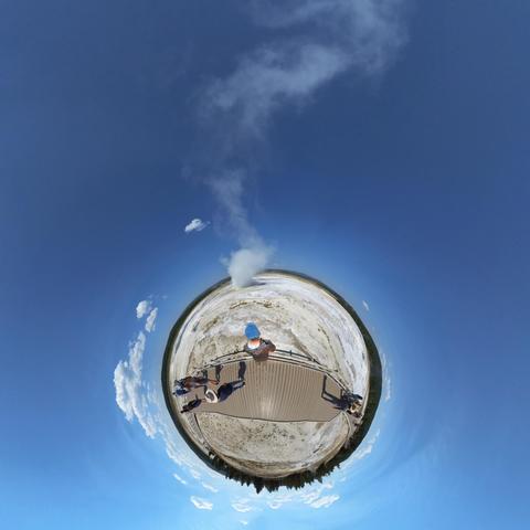 Photo of people standing on a boardwalk in a hot springs area in Yellowstone National Park.