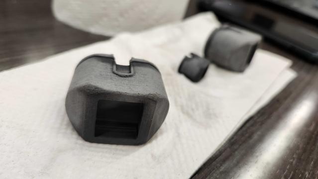 Some matte black rubbery looking gaskets sitting on a paper towel, on a faux wood table. They look like they've been roughly sanded.