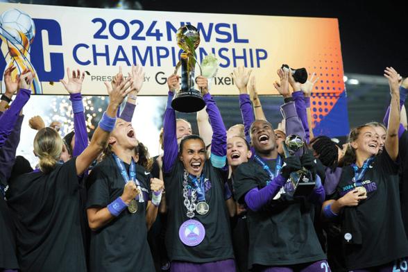 Die Spielerinnen von Orlando Pride feiern nach dem gewonnen Finale gegen Washington Spirit, Marta in der Mitte reißt die Trophäe in die Höhe, Barbra Banda direkt neben ihr feiert mit dem MVP-Pokal. Alle haben Medaillen.