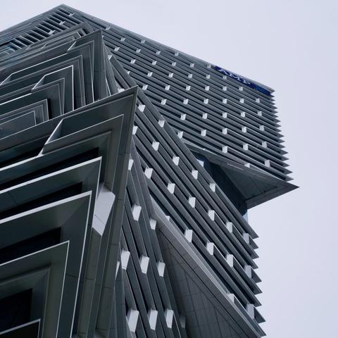 Photograph looking up at the new AMP building in Sydney.  The building is a tower of concrete and glass.  Different floors jut out at different angles, so that there are no flat sides to the tower.
