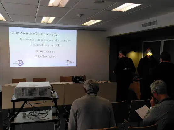 Photo du début de la présentation « OpenNebula : un hyperviseur alternatif libre,10 années d’usage au PCLL » affichant la page de titre et les intervenants se mettant en place.