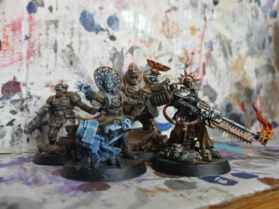 Collection of four miniatures for the Darktide tie in game by Games Workshop. A psychic levitating random objects, a soldier toting a lasgun and readying to throw a grenade, an large bald-headed man toting an oversized gun and a gas-mask wearing, flamethrower-toting religious zealot.