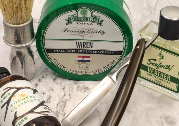 A Heljestrand straight surrounded by a tub of Stirling Varen soap, Seaforth! Heather frag, BaM Fougère Classique splash, and a Rubberset 400-3 brush with an unbleached Zenith boar knot