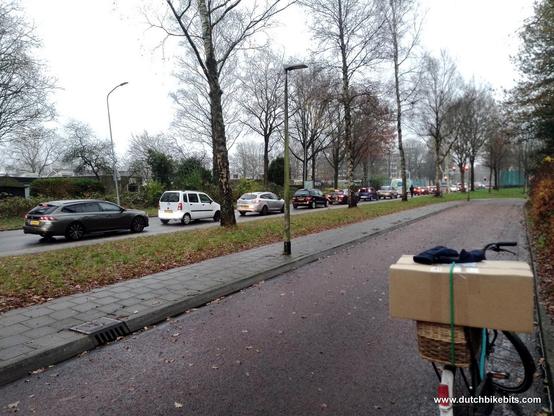An enormous queue of drivers in cars (many behind me as well as in front) waiting for a traffic light to turn green. But the cycle-path is quite empty for me so I made my journey more quickly than these drivers made theirs. Even in the Netherlands there are lots of people who are "made of sugar" and who won't cycle when there's a little rain (as there is in this photo).
