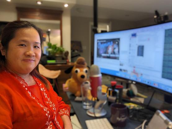Mariatta seated in her home work space, in front of the monitor showing various tabs