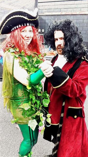Actors dressed as Captain Hook and DC comic character pose in a dance. Poison Ivy is wearing Captain Hook's hat. The photo has been digitally altered to look more like a comic book poster.