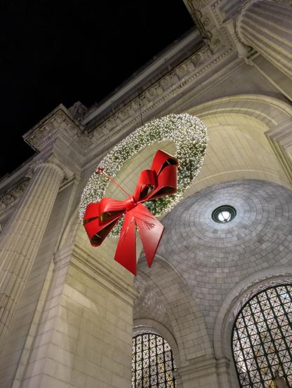 A large wreath hanging from one of Union Station's entrance arches. The wreath has a giant plastic red bow at the bottom.