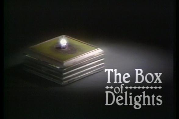 The opening of the programme The Box of Delights. To the left is the Box, which is small and square with a green top and a bright light in the centre.