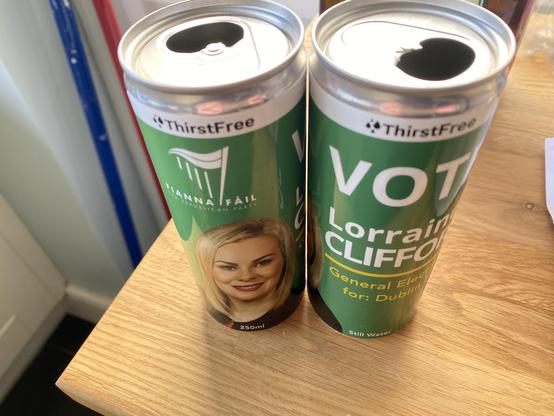 Two empty green cans of water used by a failed candidate in the recent Irish election to promote themselves. The cans show the candidates face and their name. “Fianna Fail Vote Lorraine Clifford”