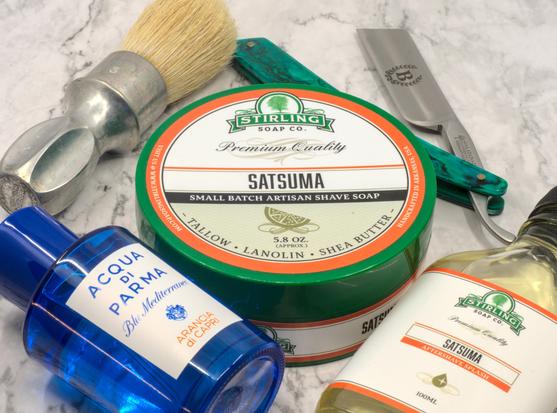 A tub of Stirling Satsuma surrounded by matching splash, a bottle of AdP Arancia di Capri frag, a Böker Abalone and a Rubberset 400 brush with an unbleached Zenith boar knot.