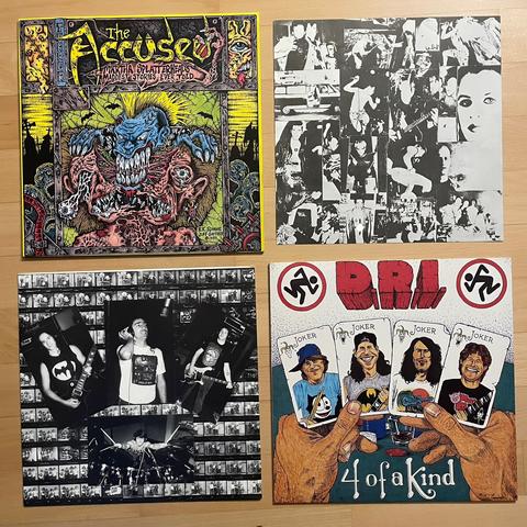 Zwei Schallplattenhüllen, jeweils daneben ist das Inlay. Links oben ist das Album „Martha Splatterhead's Maddest Stories Ever Told“ von der Band The Accüsed. Darauf abgebildet ist ein blaues Monster mit gelbem Irokesenschnitt, welches den Kopf eines anderen Monsters mit riesigen Zähnen entzweit. Daneben das Inlay mit verschiedenen schwarz-weiß Fotos. 

Darunter ist das Album „4 of a Kind“ der Band D.R.I. Darauf ist eine Zeichnung, eine Hand hält vier Karten auf denen die Band Mitglieder sind. Auf jeder Karte steht Joker.