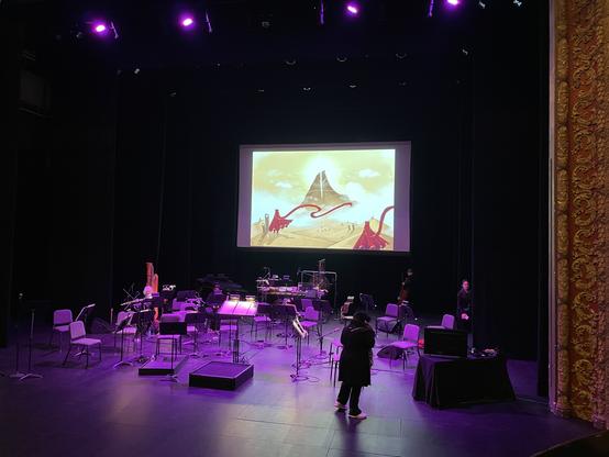 Stage set up for the orchestra with a screen showing an iconic image from Journey above