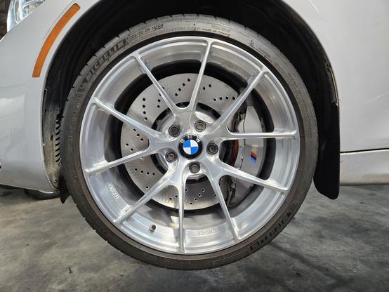 An image of a silver wheel installed on a car with a new rotor and caliper showing.