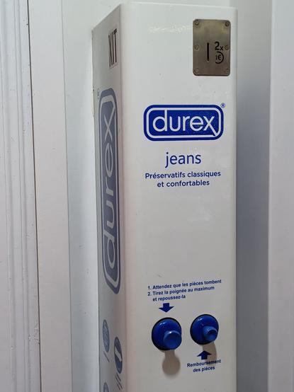 Photo of a Durex condom machine labeled "jeans" (and usage instructions in French).