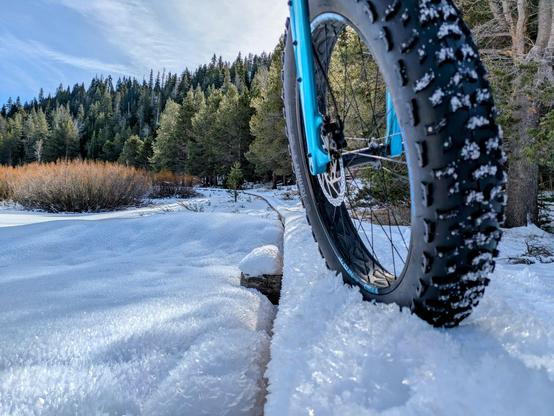 Fat bike front wheel on a raised walkway covered in ice crystals.