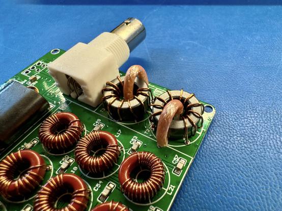 The mcHF RF board with a bunch of magnetics and the BNC connector mounted. The newly added items are  two square cross section toroids with 10 enameled wire windings each. The toroids also have one winding of a coaxial cable each. The coax provides “Faraday shielding” to provide adequate reverse isolation for the transformer.