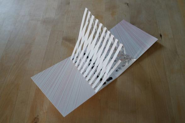 Carte kirigami pop up illustrée de lignes rouges et traces noires