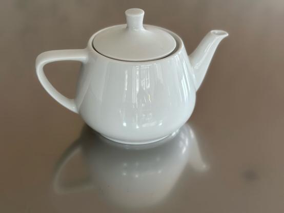 white porcelean Utah teapot on a reflective surface.