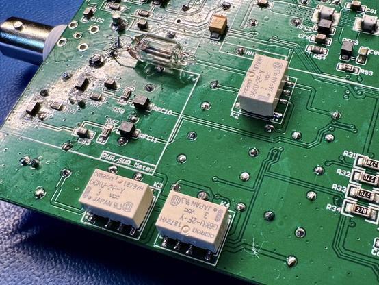 The mcHF RF board. Three white boxes which are the micro relays as well as a glass bulb with two electrodes inside. The bulb is a neon bulb connected to the antenna.