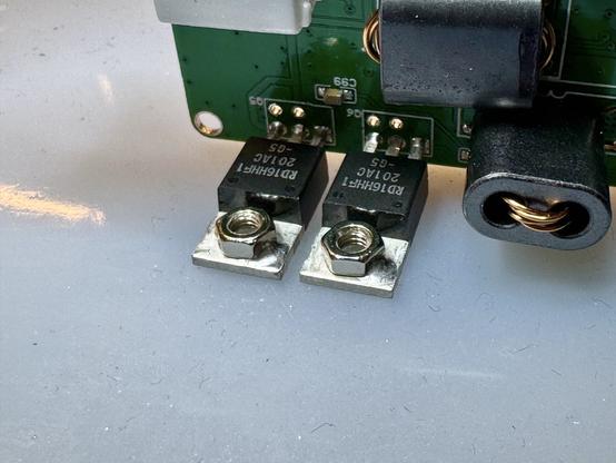 The two Power Amplifier (PA) MOSFETs in TO-220 packages. There are screw nuts on the thermal pads that have a dab of solder in the corner keeping them in place. The components are already soldered into the RF PCB.