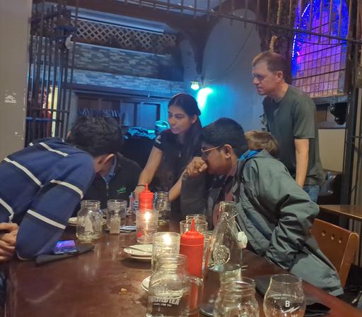A few people at a pub table looking at a laptop screen.