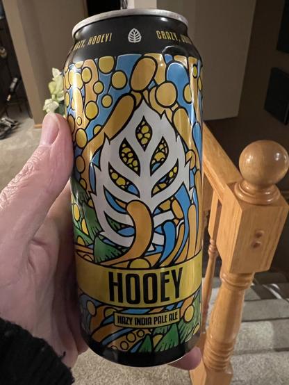 A pint can of beer is decorated in orange and yellow and white and green and blue in a weird psychedelic pattern.