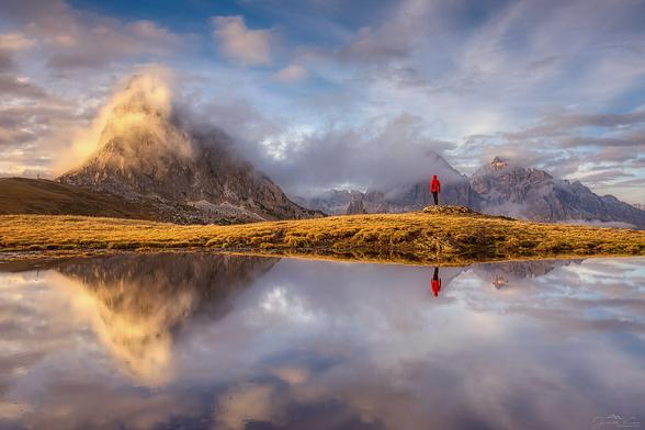 At Passo Giau there is a small pond, actually just a wet spot in the meadow, in which the peaks of Ra Gusela and Tofana di Rozes are reflected when the weather is calm. When I arrived at this little pond, a workshop with eight photographers was already set up there. Fortunately, a seemingly unattractive spot was still free and I was able to set up my tripod. I don't know why the spot was left free, because I thought it was ideal. As the mountains slowly emerged from the clouds, the workshop leader posed for his participants in front of the mountains. I generally prefer landscape photos without people, but here I actually like the counterpoint quite well. I also have almost the same version of the photos without the workshop leader, but with a bit more Tofana...