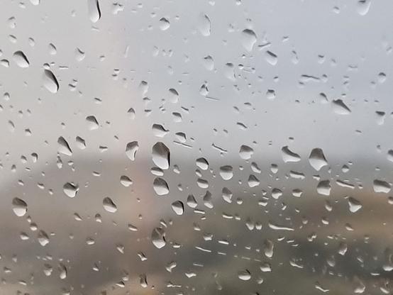 Gocce di pioggia sospese sul finestrino mentre fuori si forma un delicato arcobaleno