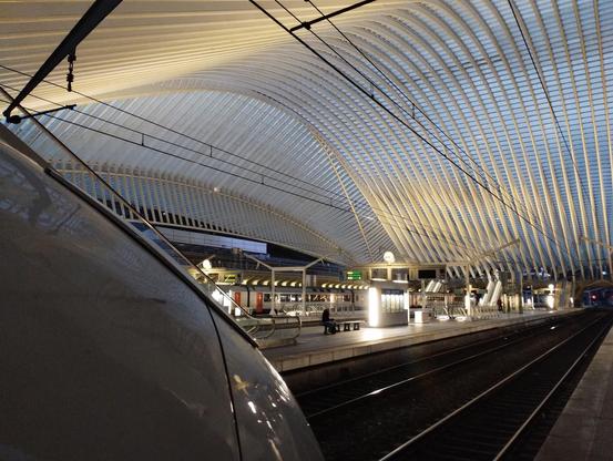 The nose of a DB ICE3 with the swooping trainshed of Liège Guillemins.