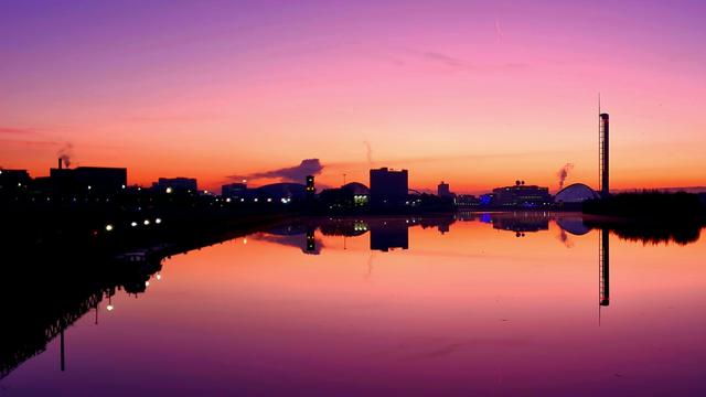 Looking east along the Clyde towards the rising sun, with the modern buildings of Glasgow's waterfont visible on the horizon.