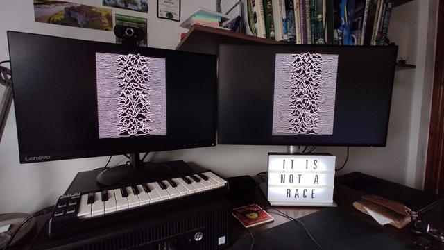 Lightbox with lettering "IT IS NOT A RACE" under 2 monitors