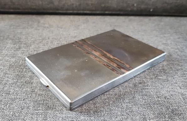 A slightly tarnished silver cigarette case, rectangular in shape with three copper coloured bands across the middle.