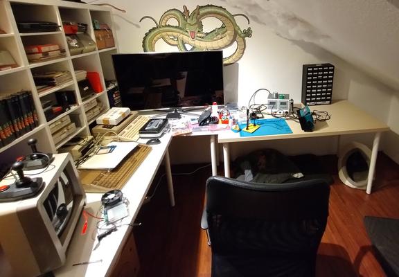 the new electronics hobby corner. on the left are the retro computers: two C64s, a C128, and an Amiga 500. at the wall is a table with the soldering station. undern the table is a cat's nest.