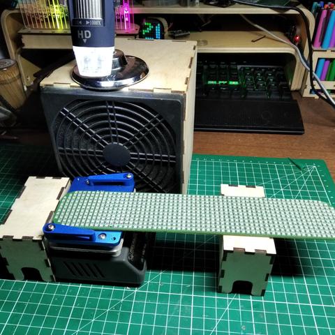 The pcb now has all its led.
It's sitting on top of a small heating table. As the table is to small (60x80mm) for the pcb (45x240mm), a big part of it is not and the table and supported by a wooden box.
The table is in front of 120mm extractor fan.
On top of the fan (whose body is a wooden box) stands an alectronic microscope pointing at the pcb.