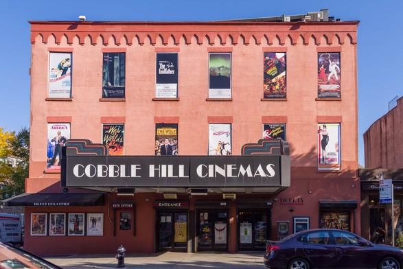An old cinema in the style of the 70s. Film posters announce films from this period.