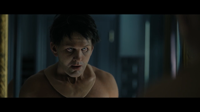 A serial killer stands in front of a mirror wearing a mask that resembles Graham Linehan's ugly mug.