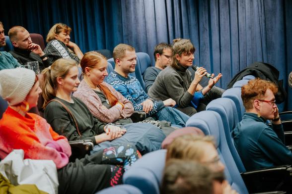 People having a Q&A session in a cinema. One woman is having a microphone and is asking a question.