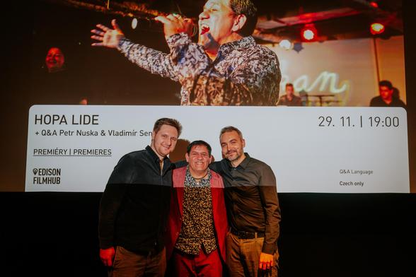 Three men taking a photo in a cinema before the screen, which says: "Hopa lide + Q&A Petr Nuska & Vladimir Sendrei"