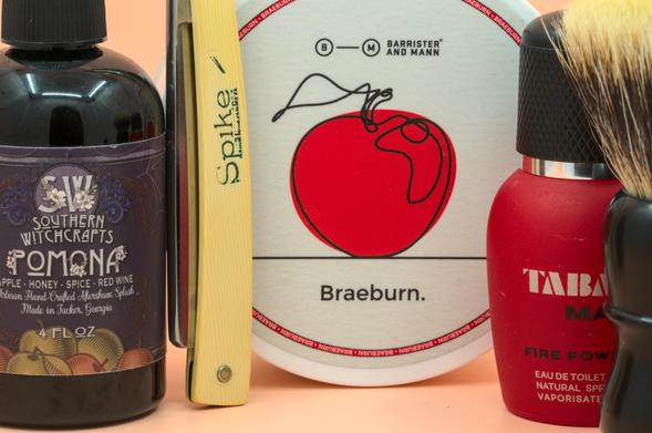 A Spike wedge razor leaning against a tub of BaM Braeburn soap between SW Pomona splash, Tabac Man Fire Power frag, and a Dogclaration Mystery B16 brush